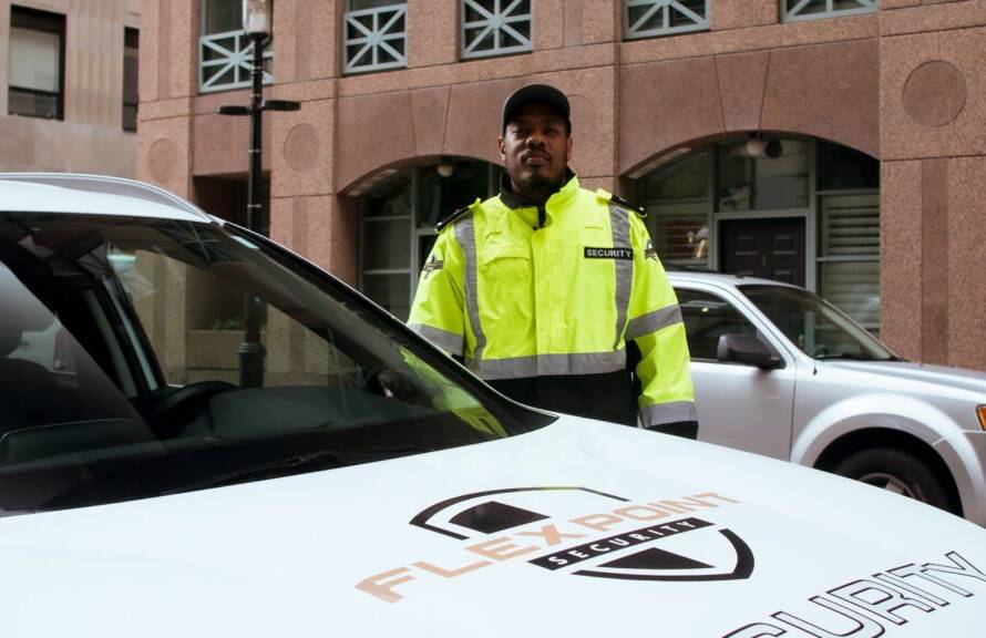 A male Flex Point Security guard standing next to a company vehicle in Downtown, Toronto