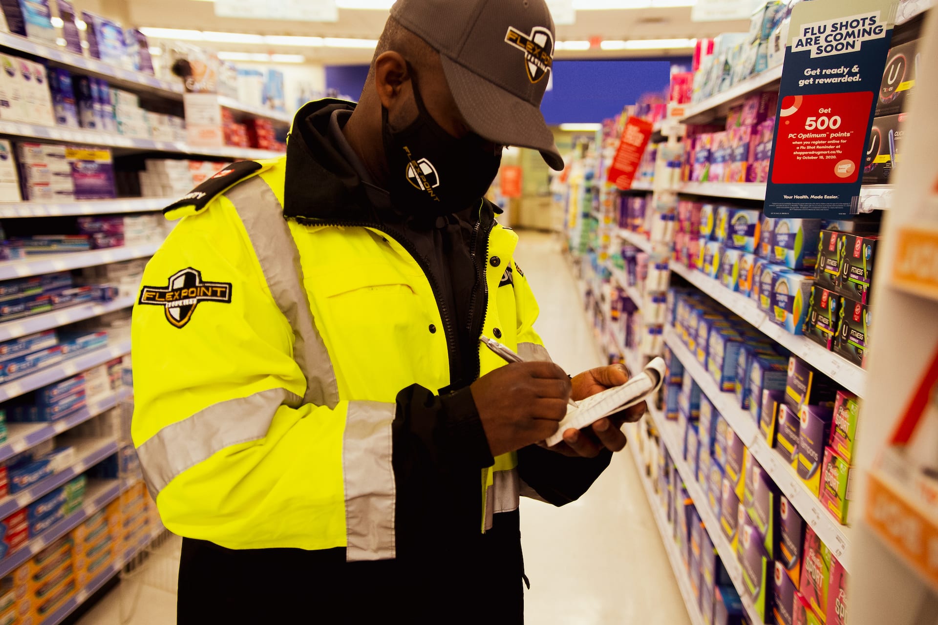 Flex Point Security guard writing on a notepad as he provides loss prevention security services at a retail store