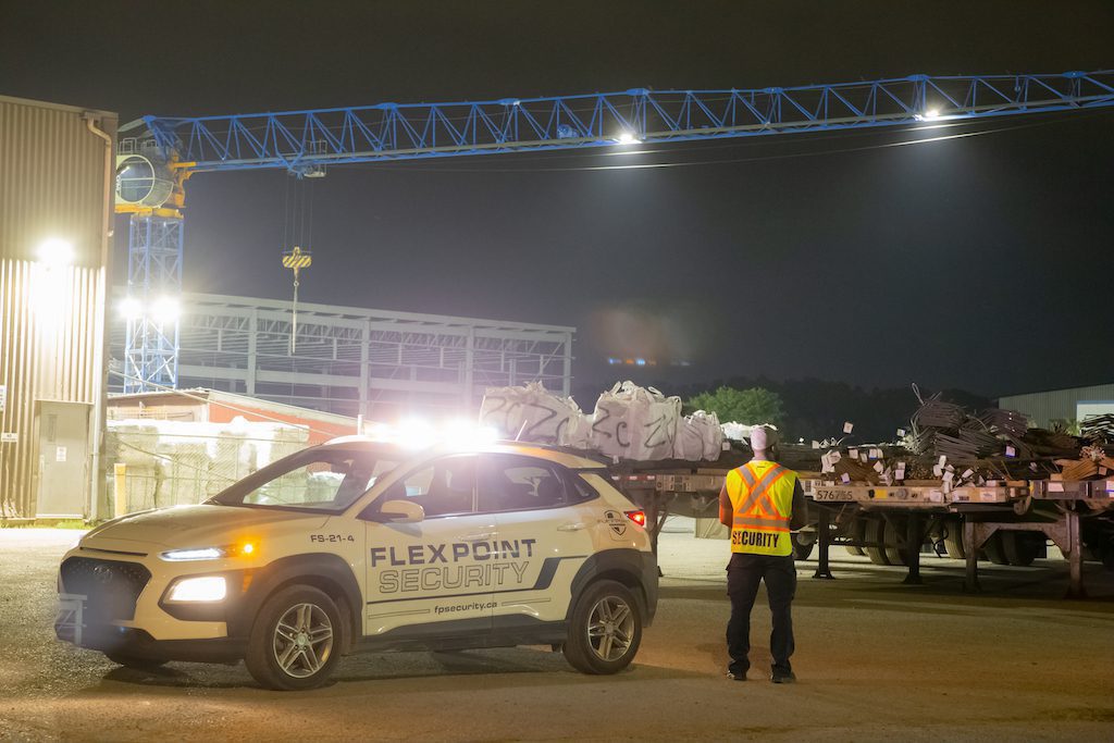 Flex Point Security guard standing next to company vehicle as he monitors a logistics site