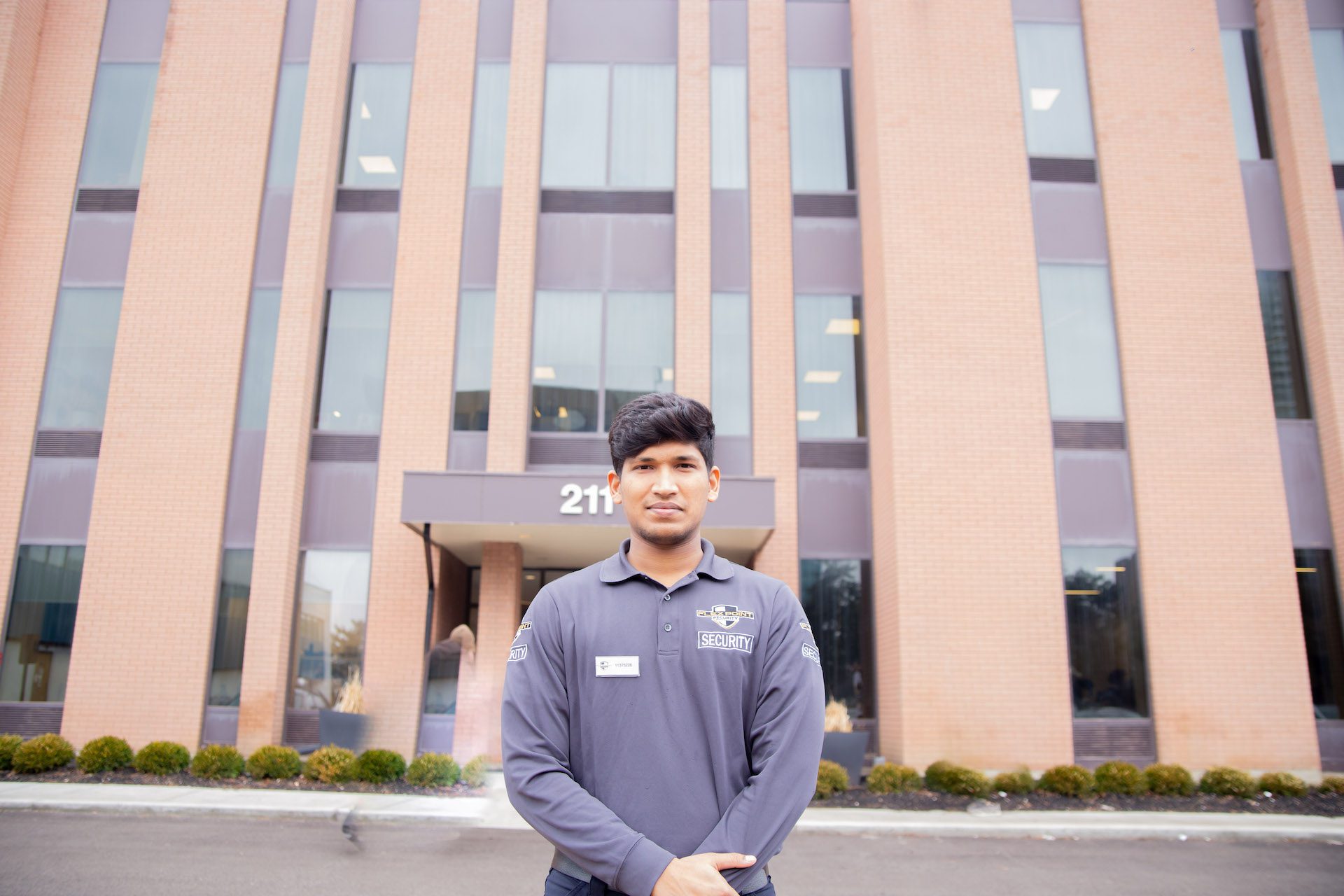 A Flex Point Security guard standing with his arms crossed outside of an office building