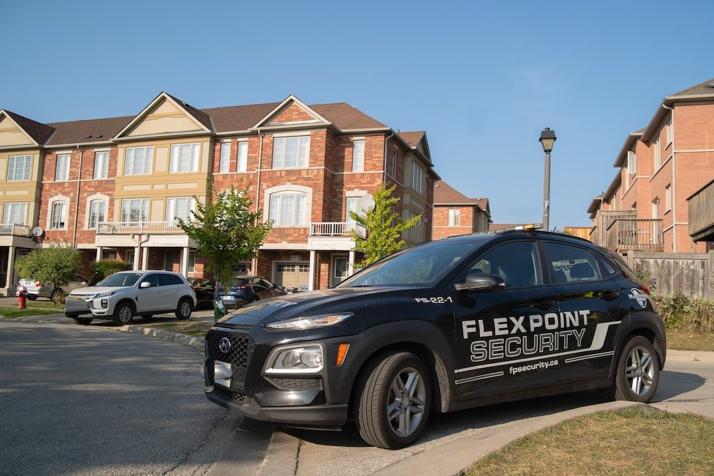 A black Flex Point Security vehicle patrolling in a neighbourhood complex