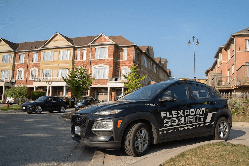 A black Flex Point Security vehicle patrolling in a neighbourhood complex