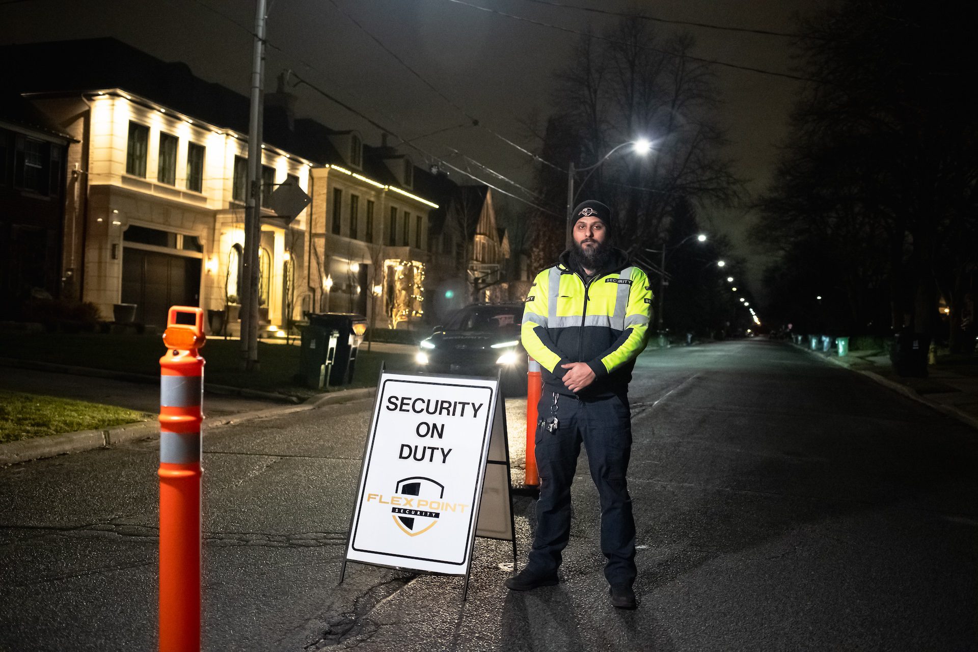 A male Flex Point Security guard standing next to a "Security on Duty" sign while providing Neighbourhood Watch services