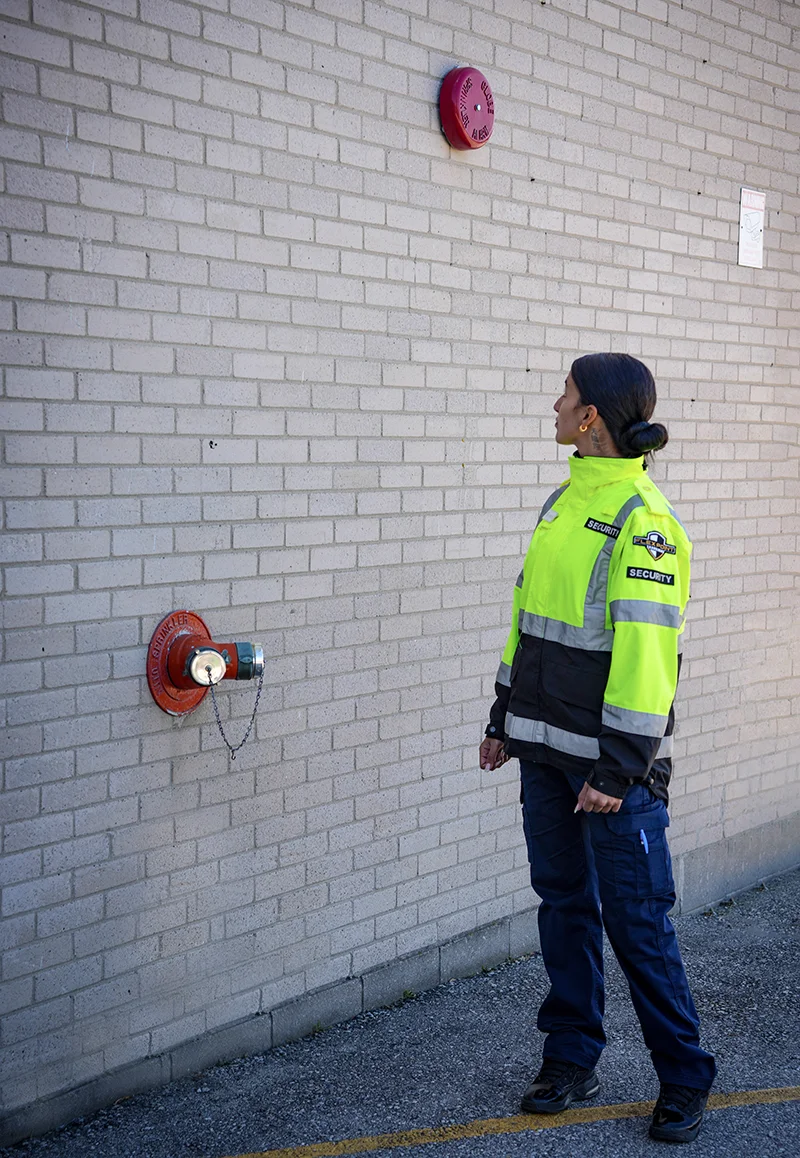 A female Flex Point Security guard outside of a building conducting fire watch duties
