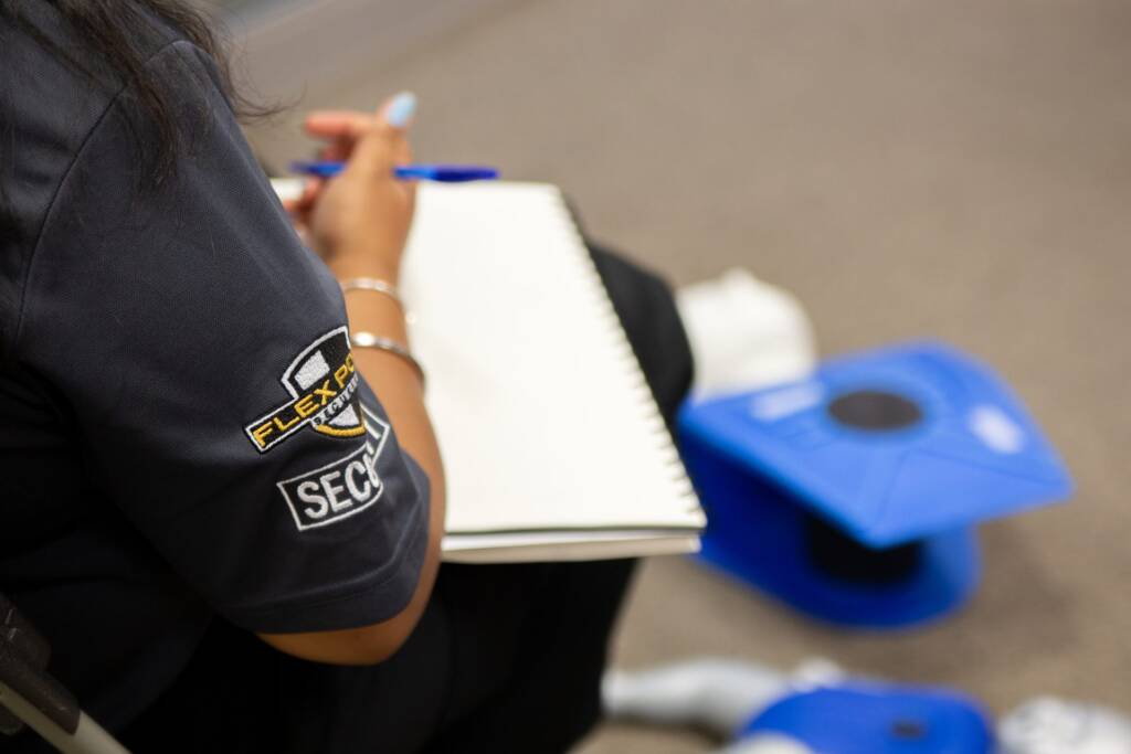 Close up of a female security guard trainee writing notes during first aid and CPR training