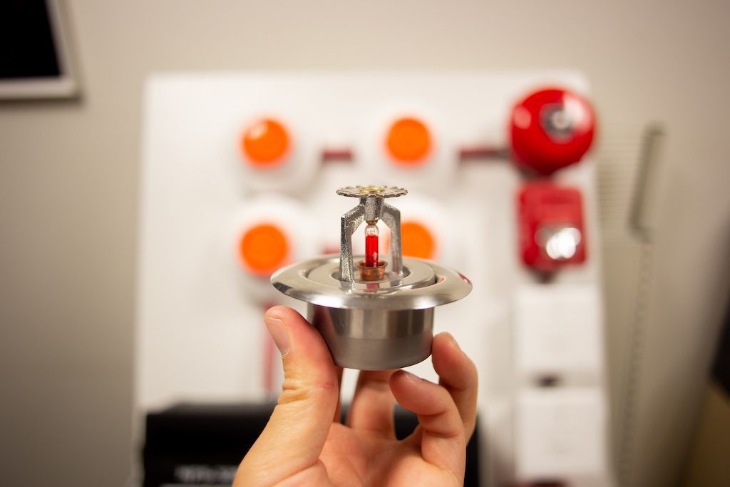 Close up of someone's hand as they hold a fire alarm water sprinkler