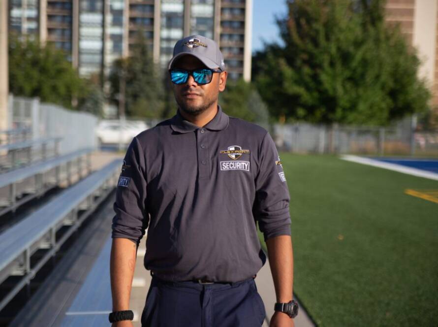 A Flex Point Security guard walking down a football field next to bleachers