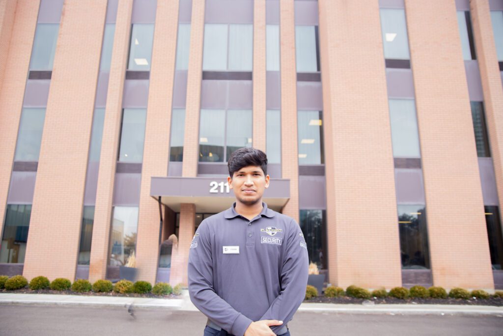 A male Flex Point Security guard standing in front of a corporate building