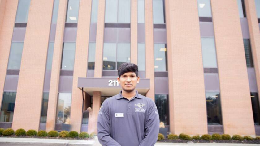 A male Flex Point Security guard standing in front of a corporate building