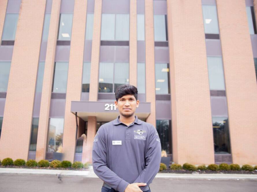 A male Flex Point Security guard standing in front of a corporate building