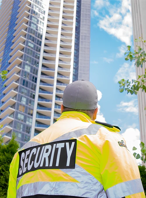 Flex Point Security guard looking up at two condos where he provides residential security services