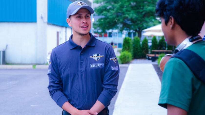 A male Flex Point Security guard speaking with a student while on campus patrolling