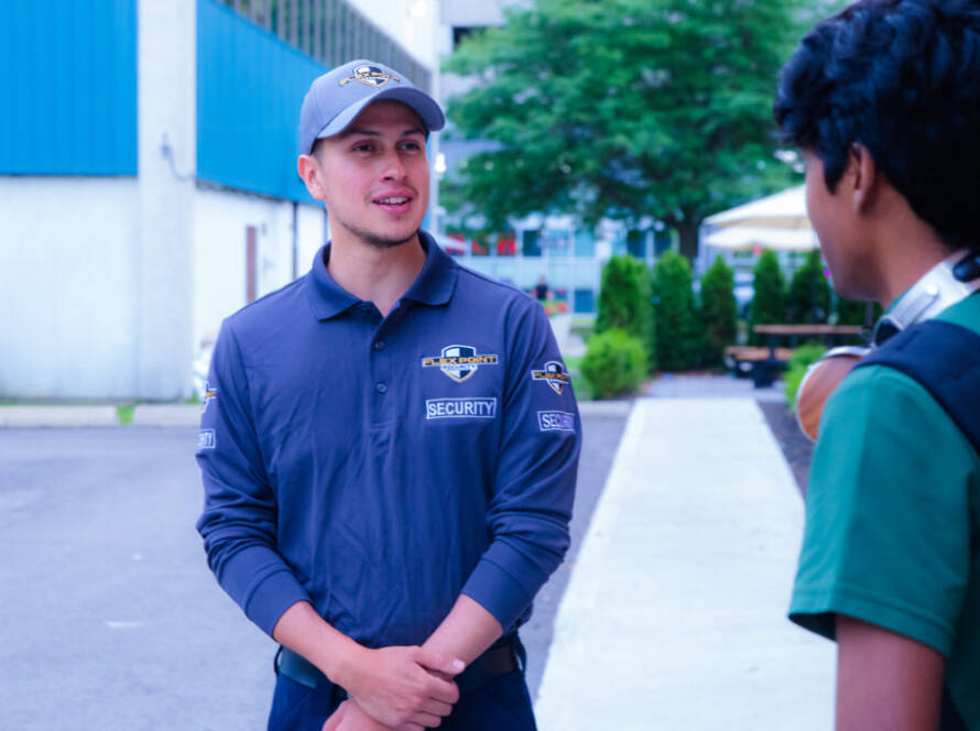 A male Flex Point Security guard speaking with a student while on campus patrolling