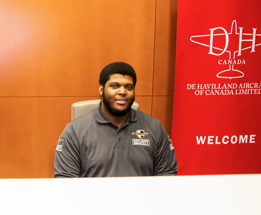 A male Flex Point Security guard seated at a front desk while providing concierge services for a corporate client