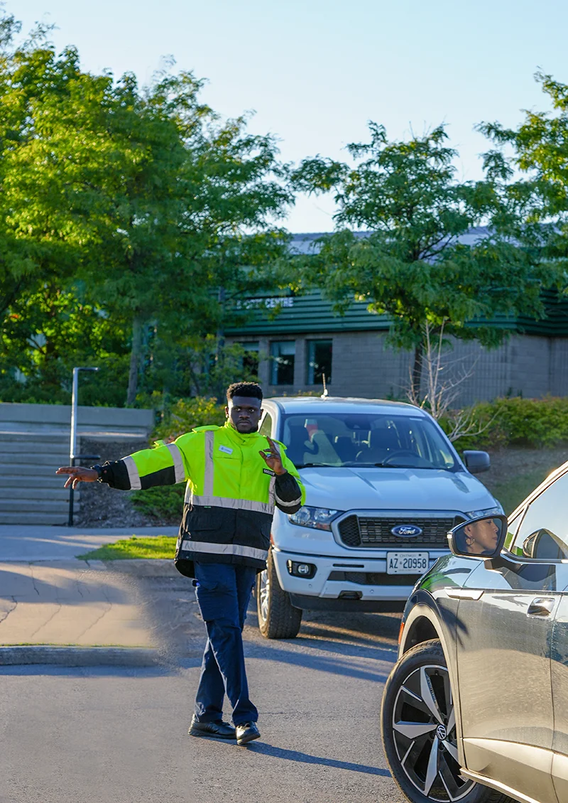A male Flex Point Security guard providing parking enforcement services by directly vehicles in a parking lot
