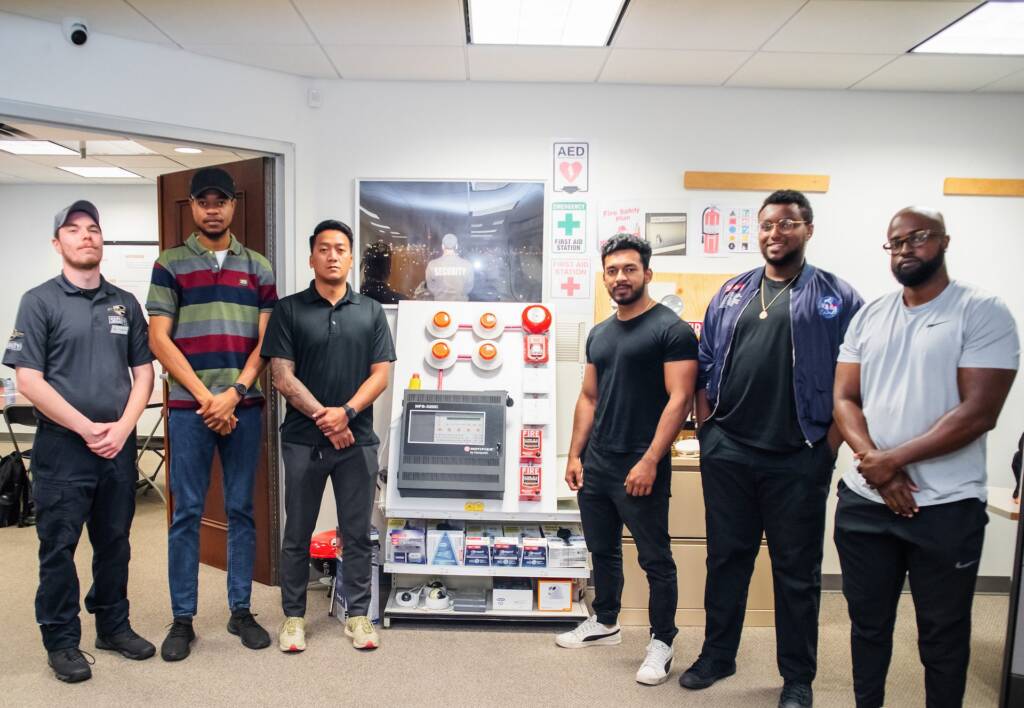 5 Flex Point Academy trainees standing next to a male Flex Point Security guard in the Flex Point Academy training office