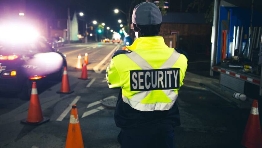 A male Flex Point Security guard standing while on-site at night at a construction site