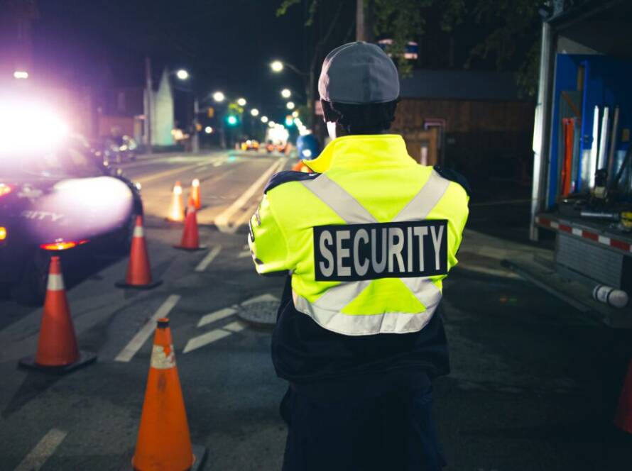 A male Flex Point Security guard standing while on-site at night at a construction site